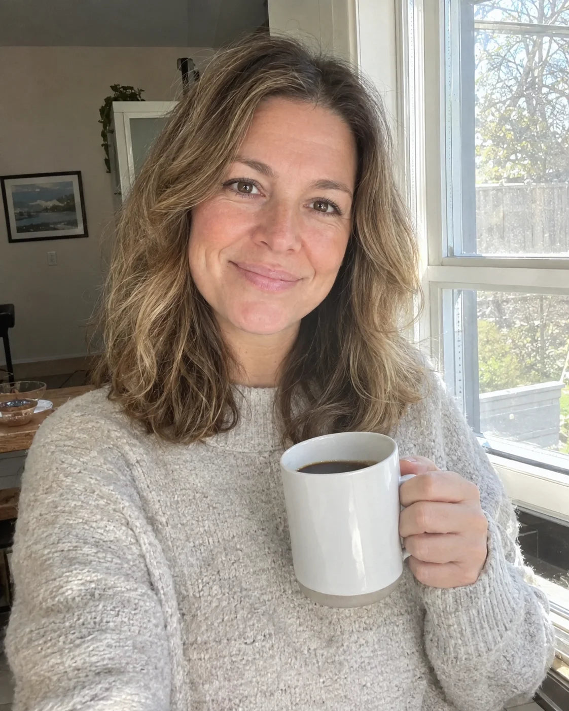 Woman calm and rested, holding a mug of coffee in morning light