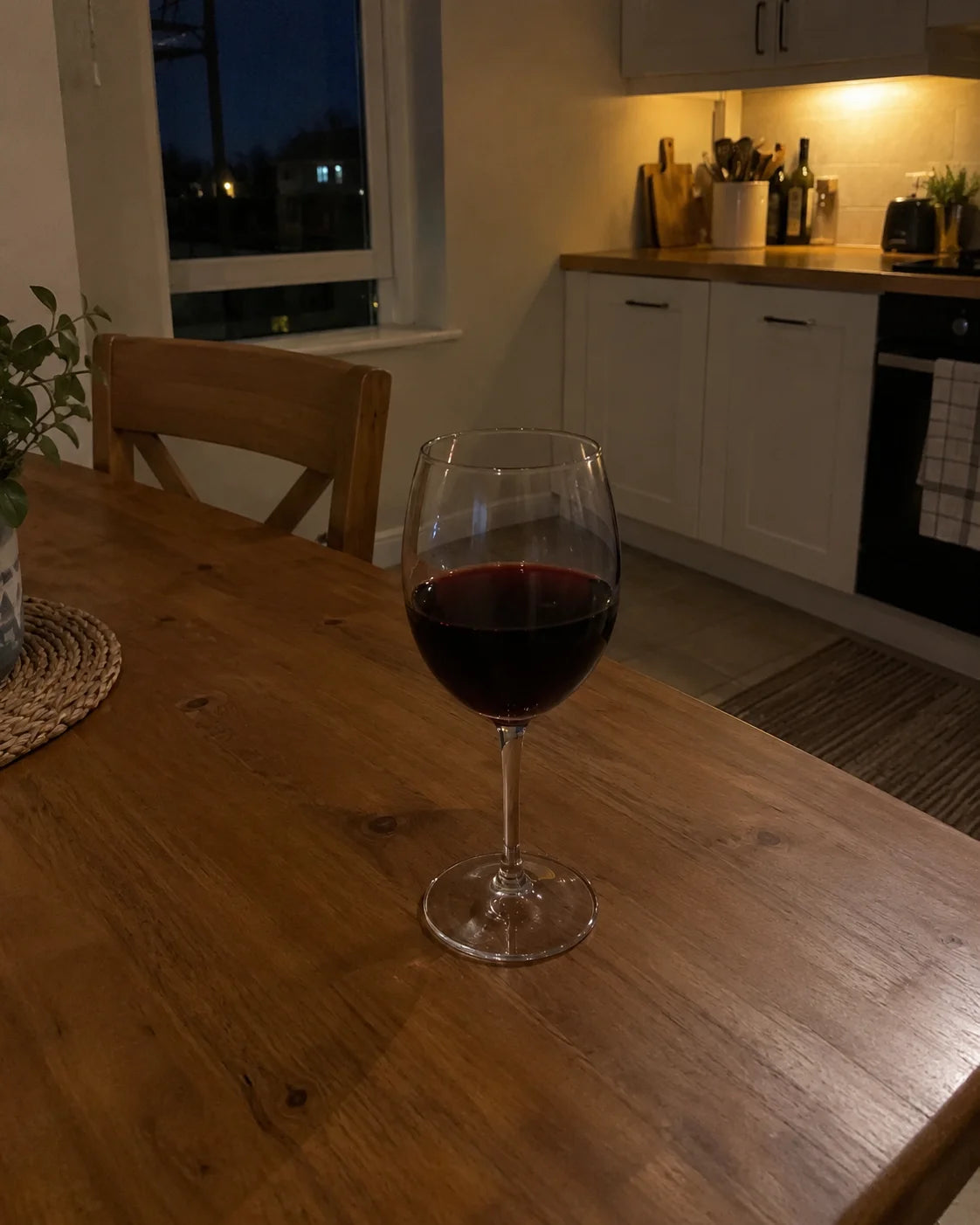 Single glass of wine alone on a dinner table at night