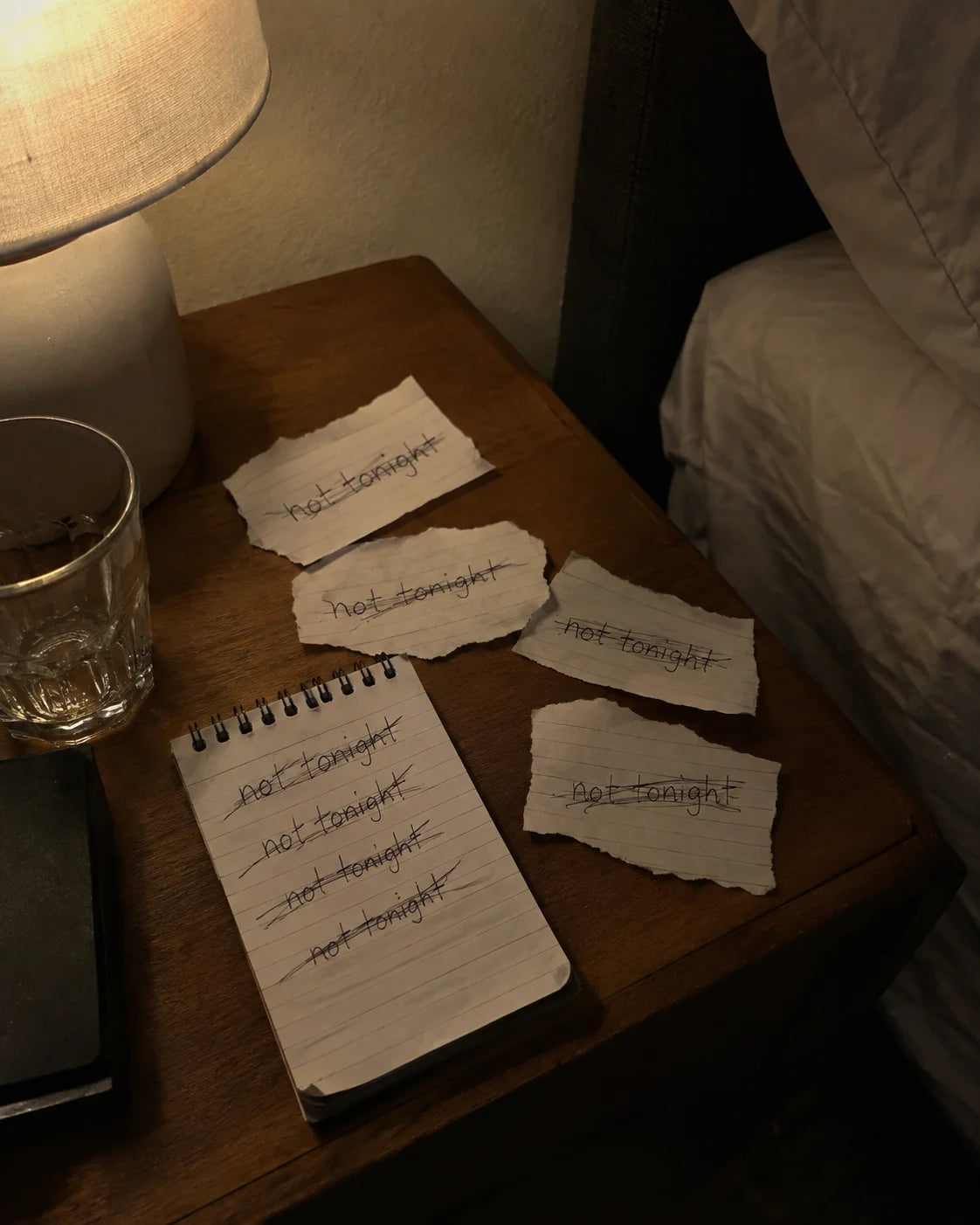 Notepad on a nightstand with 'not tonight' written and crossed out again and again