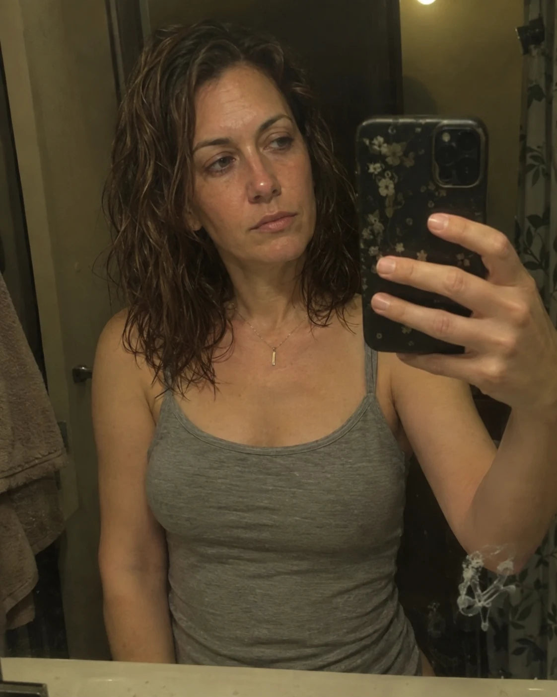 Woman's quiet mirror selfie late at night, worn expression