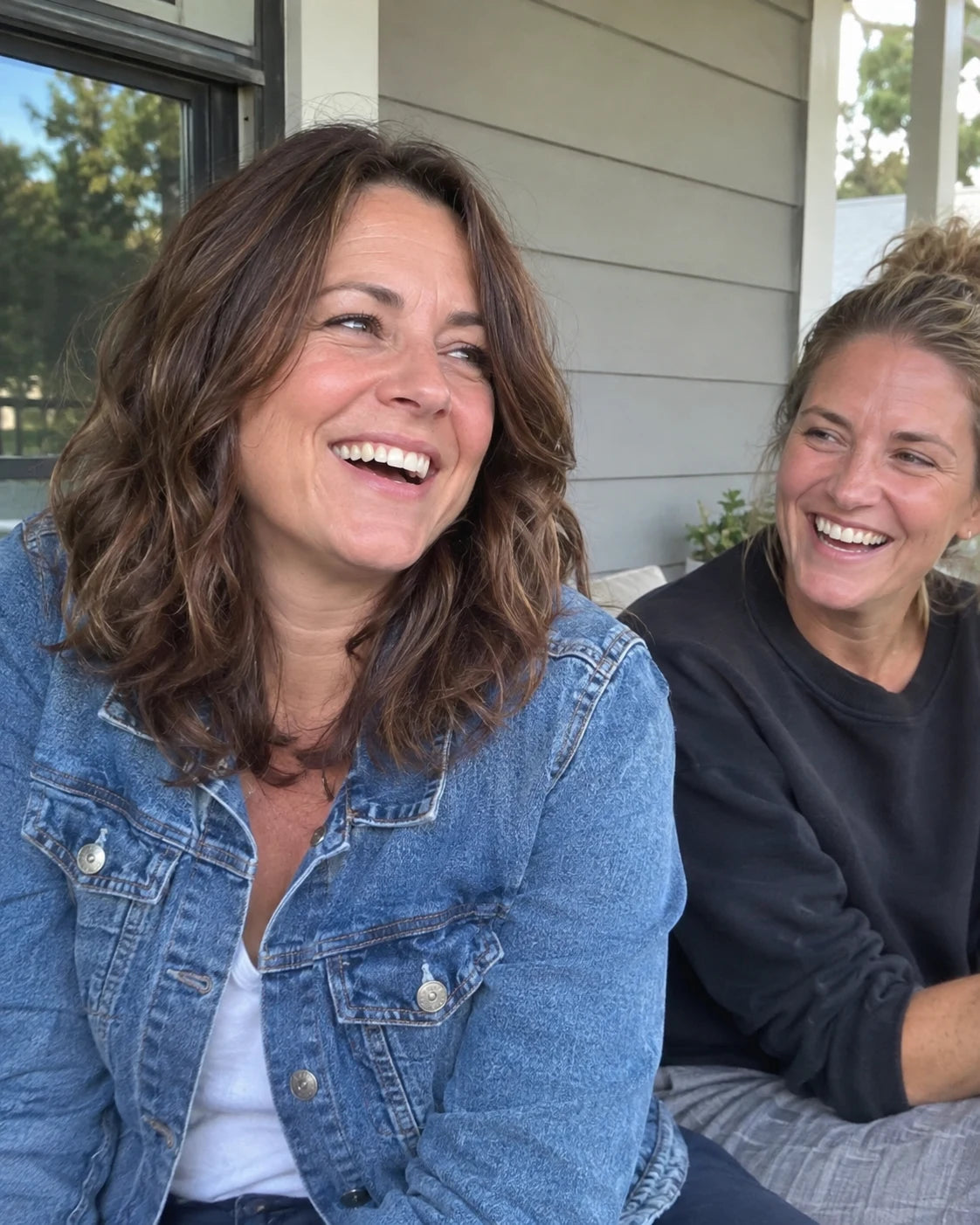 Two friends laughing together outdoors in late afternoon light