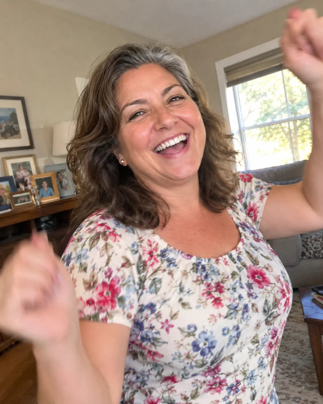 A woman laughing and dancing with her kids in a sunlit living room