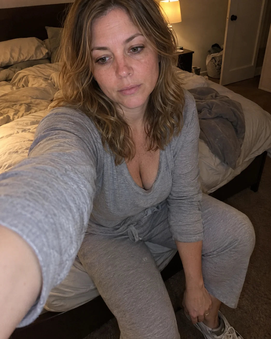 Woman sitting on the edge of her bed in the evening, exhausted