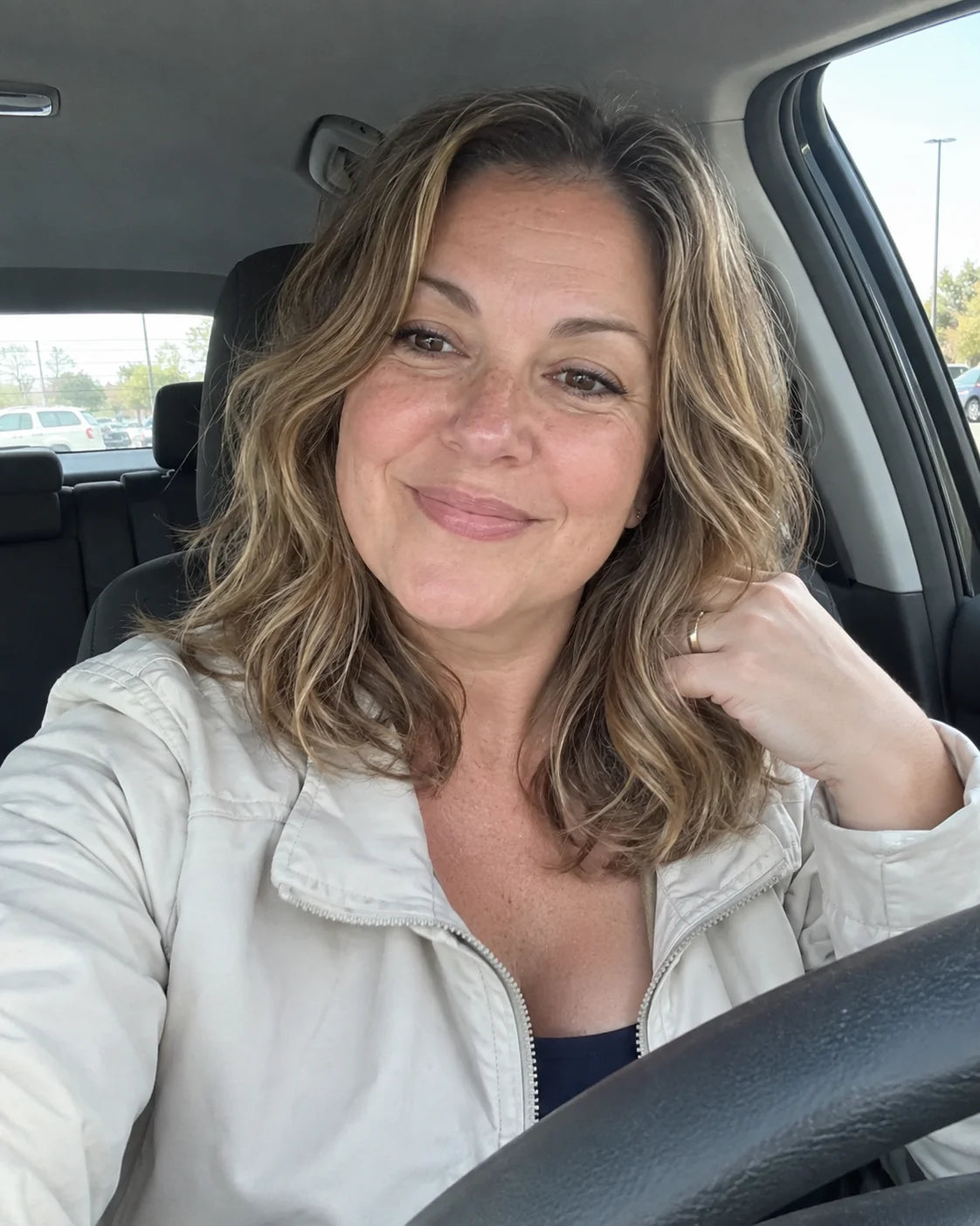 Woman smiling behind the wheel of her parked car in daylight