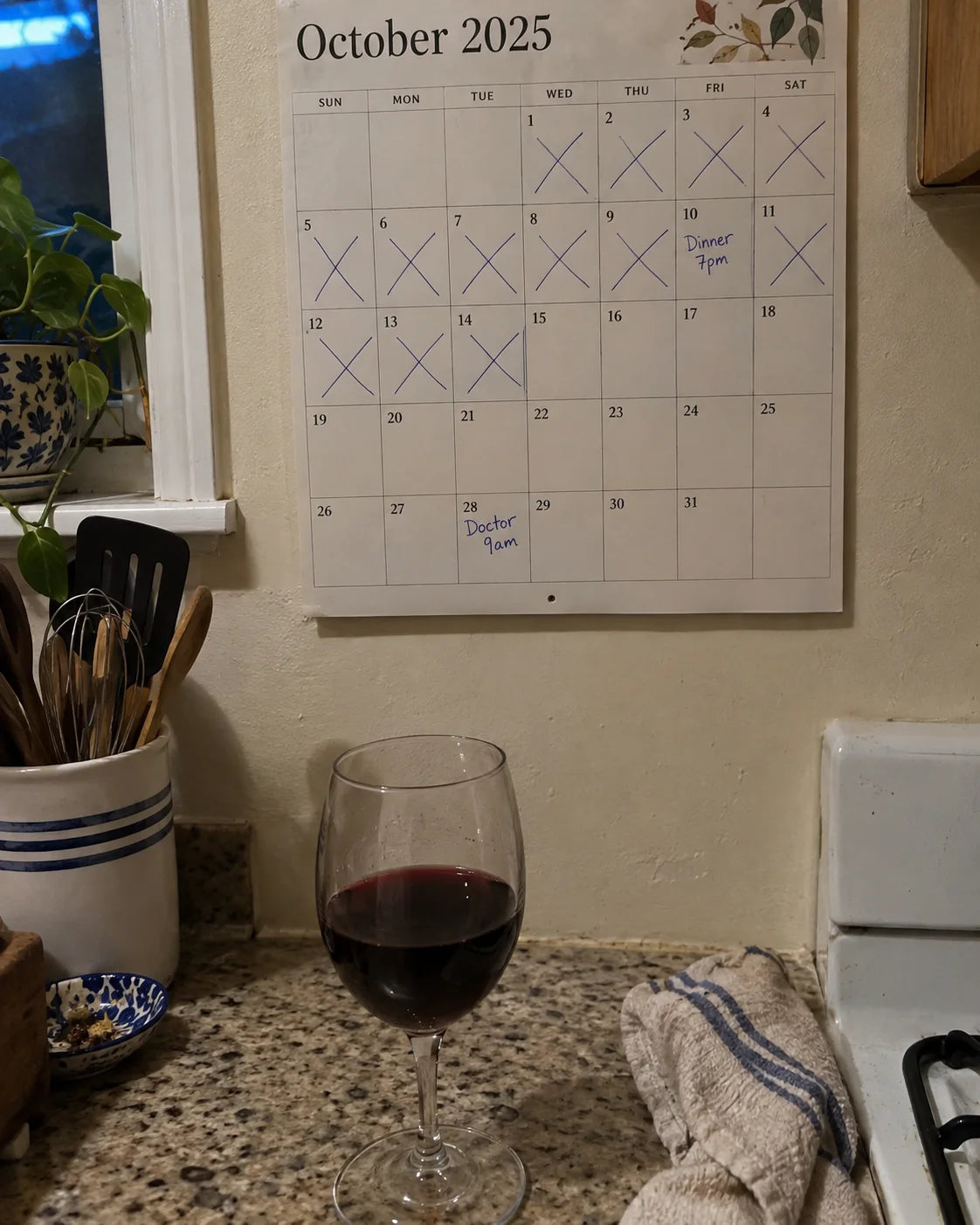 Kitchen calendar with weekdays crossed out and a glass of wine on the counter below it