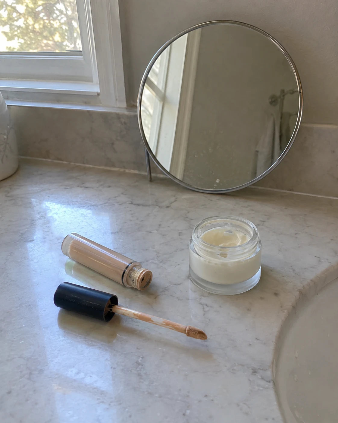 Concealer and under-eye cream left out on a bathroom counter, used every morning