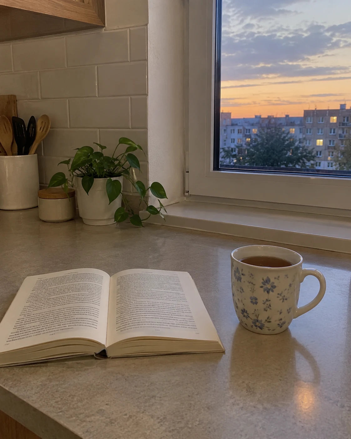 A calm kitchen counter at 6pm with a mug of tea and an open book, no wine in sight