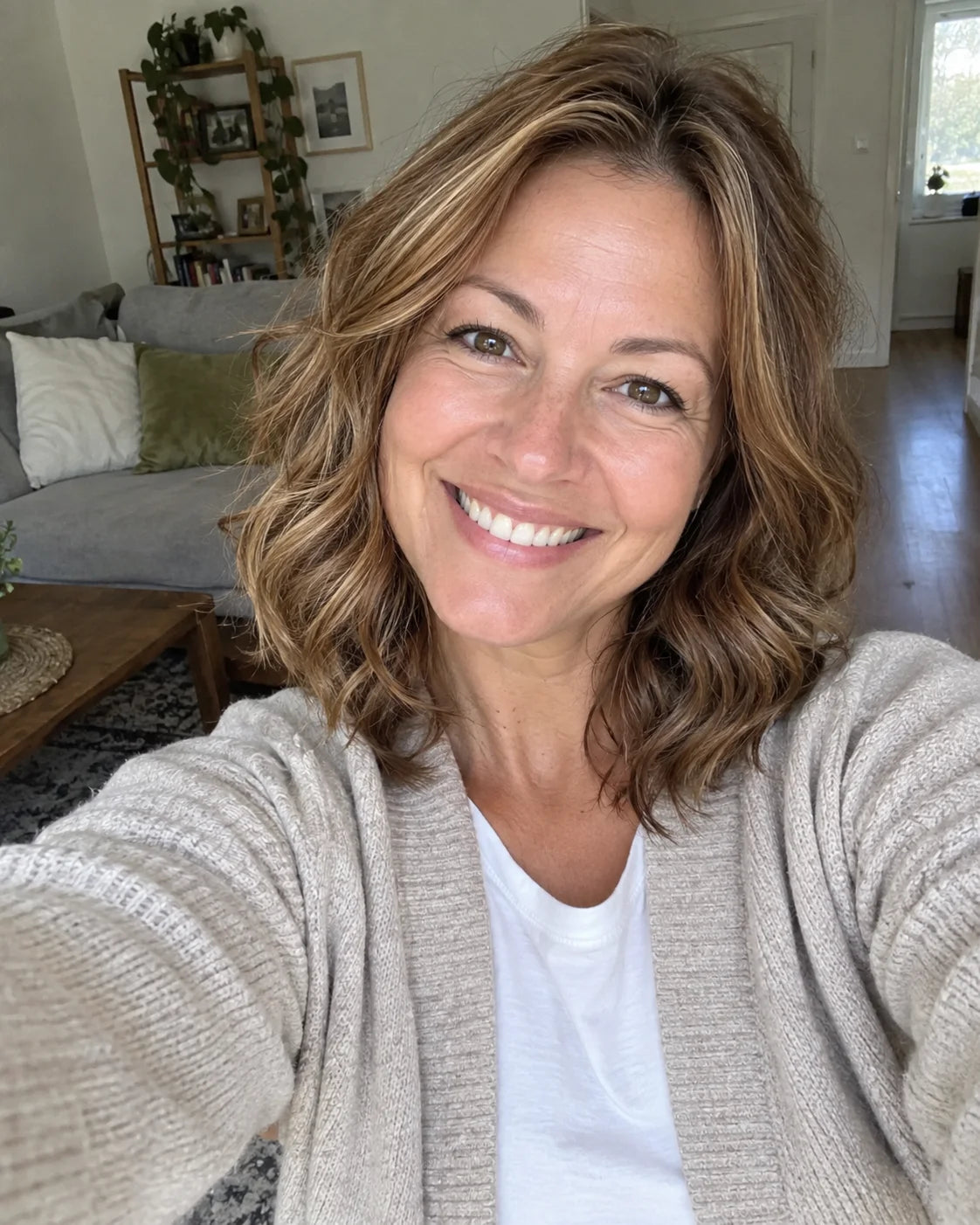 Selfie of a woman smiling warmly and genuinely, holding her phone up to take the photo