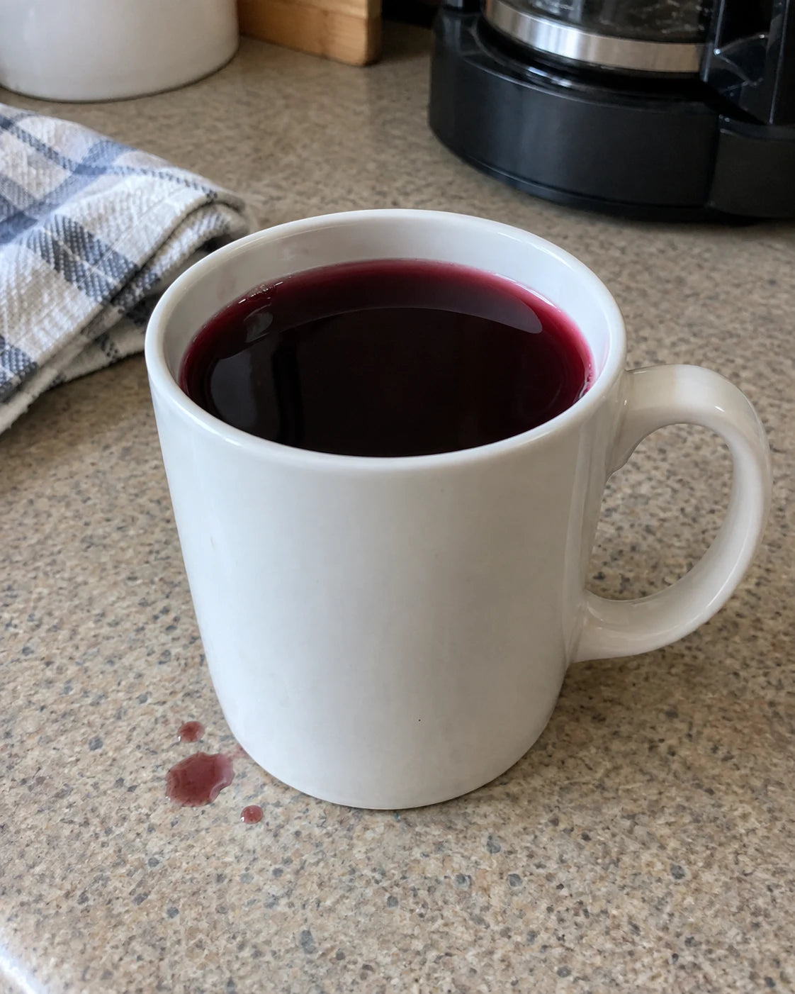 Wine poured into a plain coffee mug on a kitchen counter