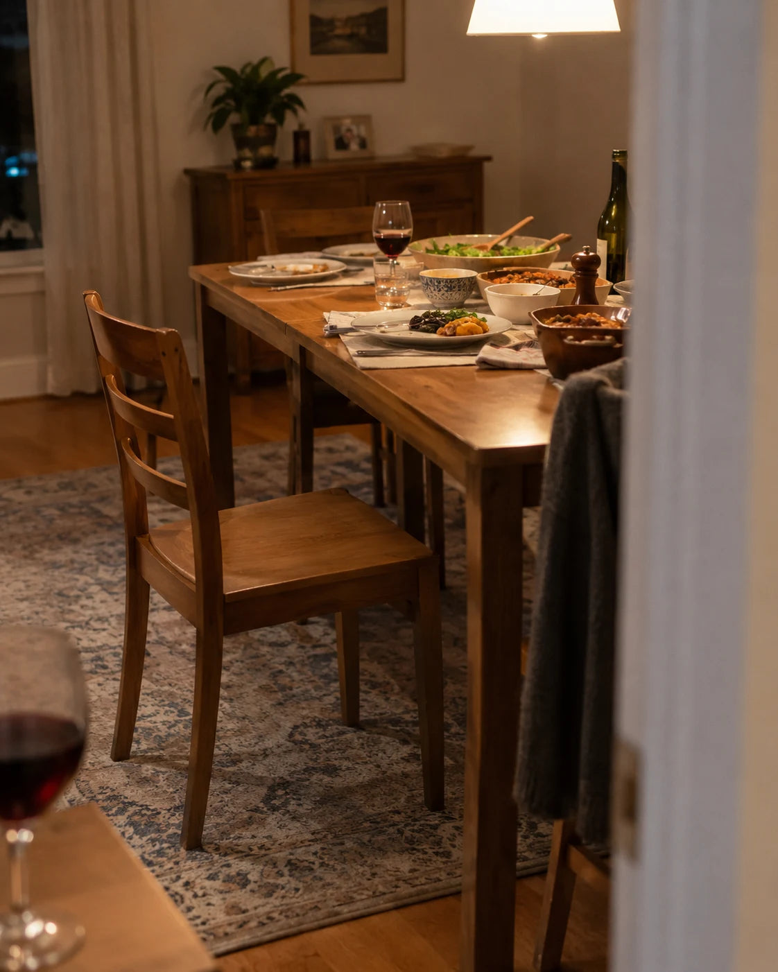 Family dinner table with an empty chair and a wine glass blurred in the foreground