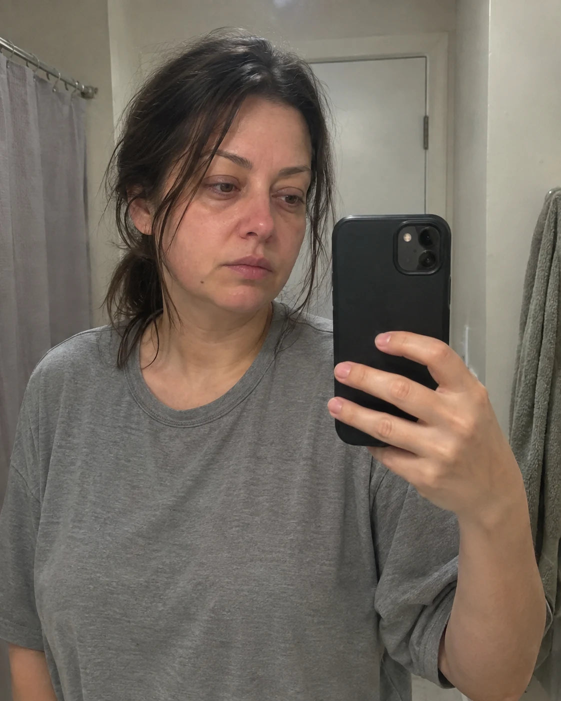 Woman's tired mirror selfie at night, worn expression