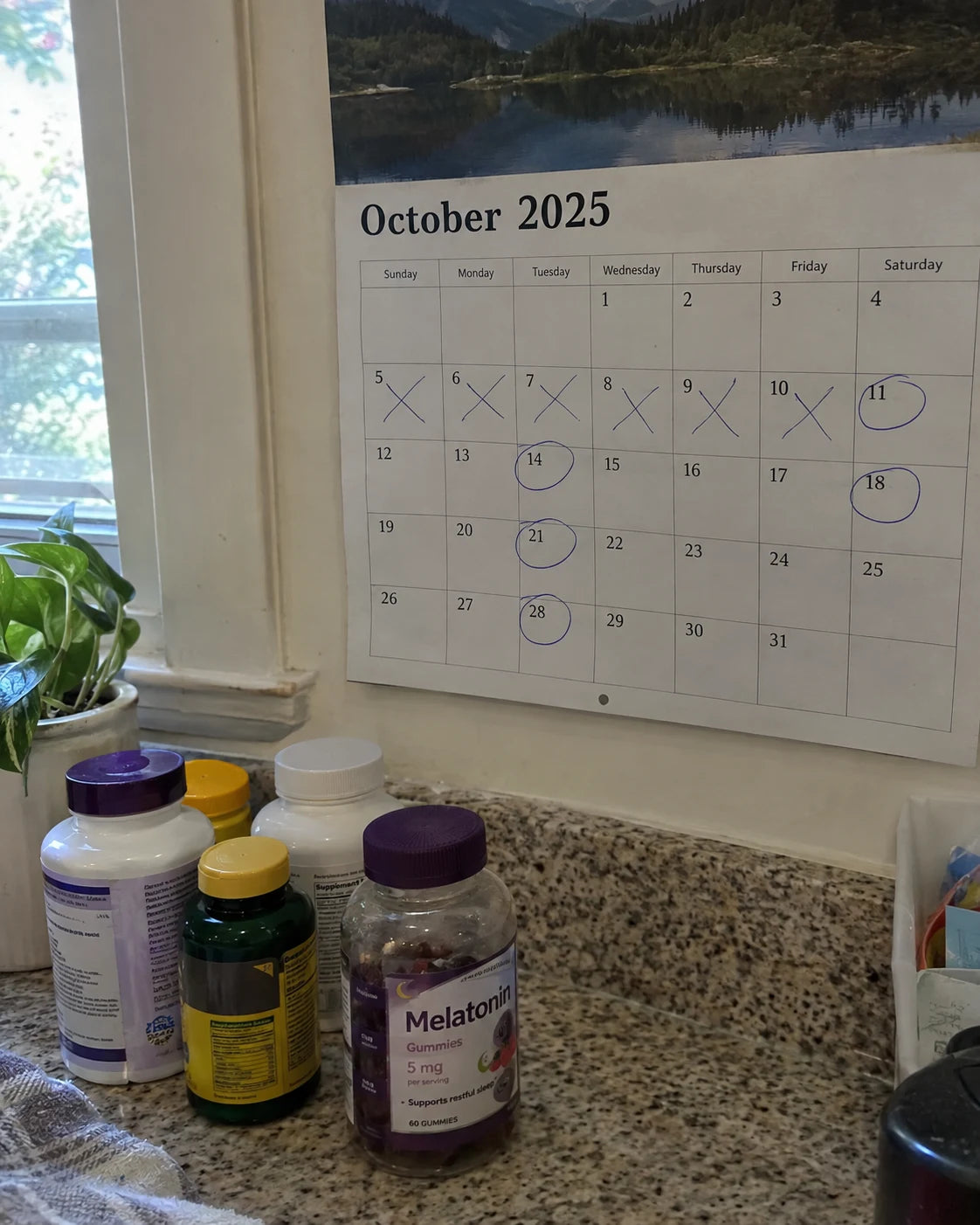 A kitchen calendar with dates crossed out next to a cluttered counter of unlabeled supplement bottles