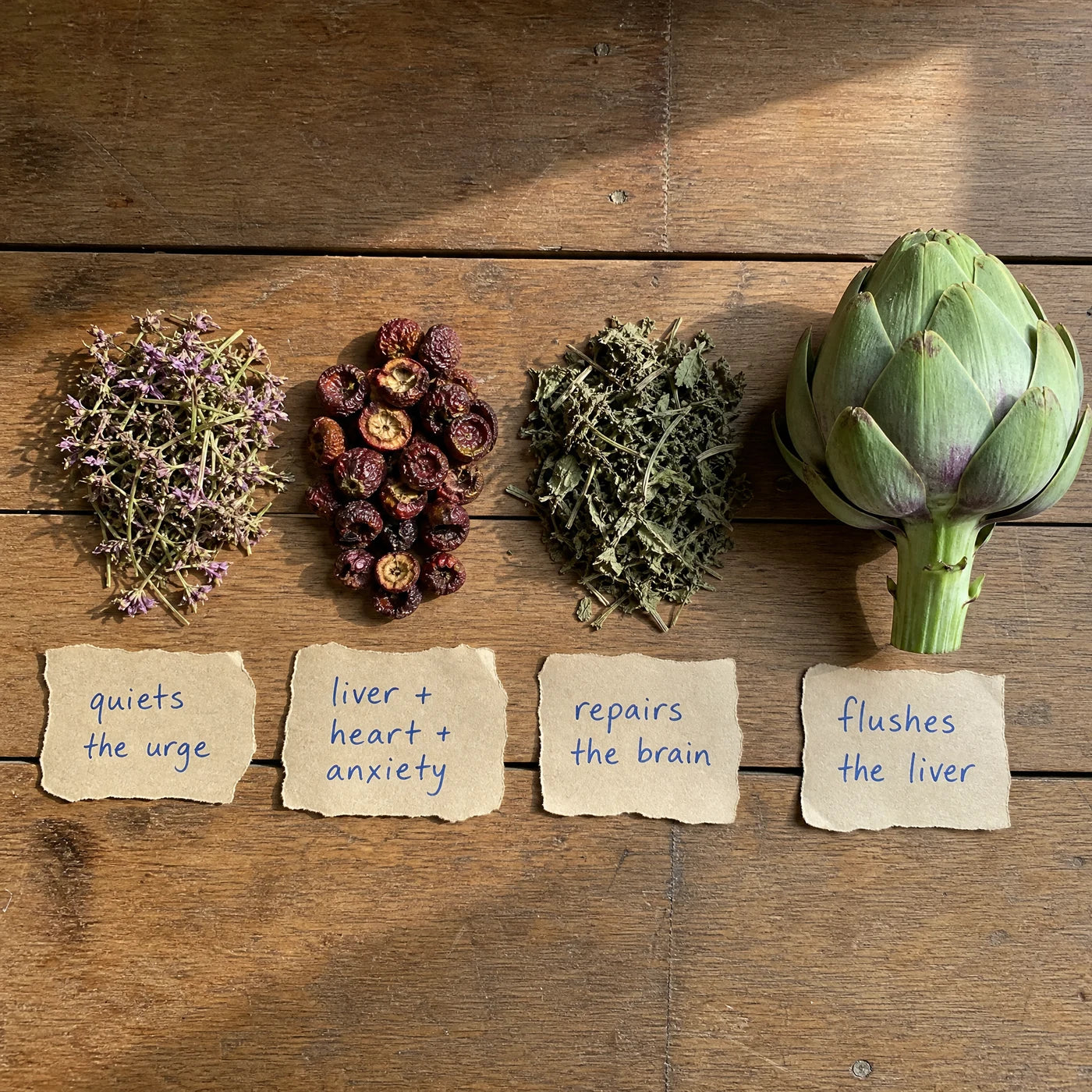 Four dried herbal plant ingredients laid out on a wooden table, each labeled with its job