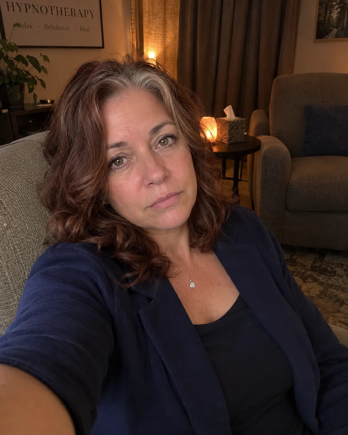 A tired woman taking a selfie in a waiting room chair after a hypnosis session