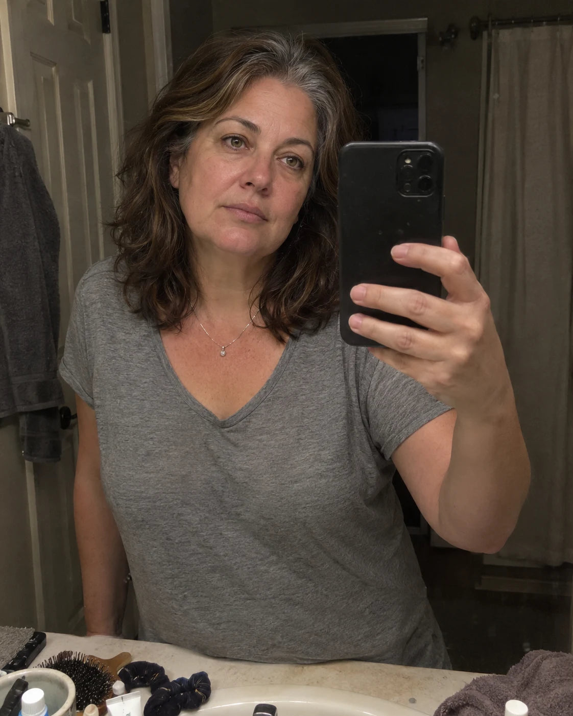 Woman's tired mirror selfie at night, phone visible in her hand