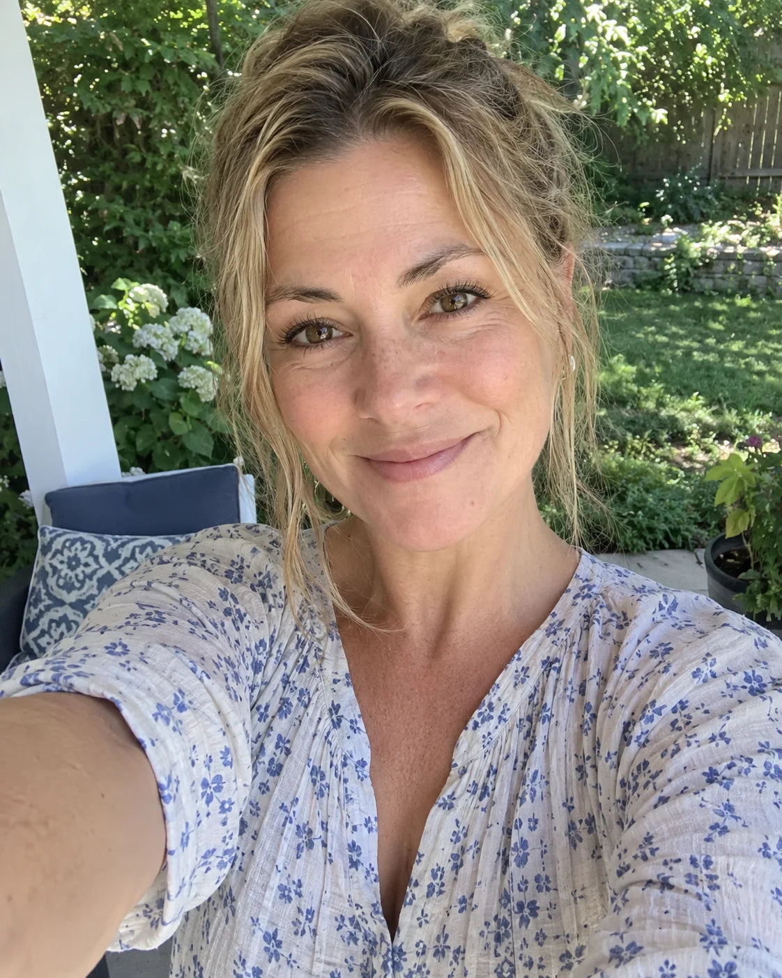 A woman smiling outdoors in natural sunlight, relaxed and free