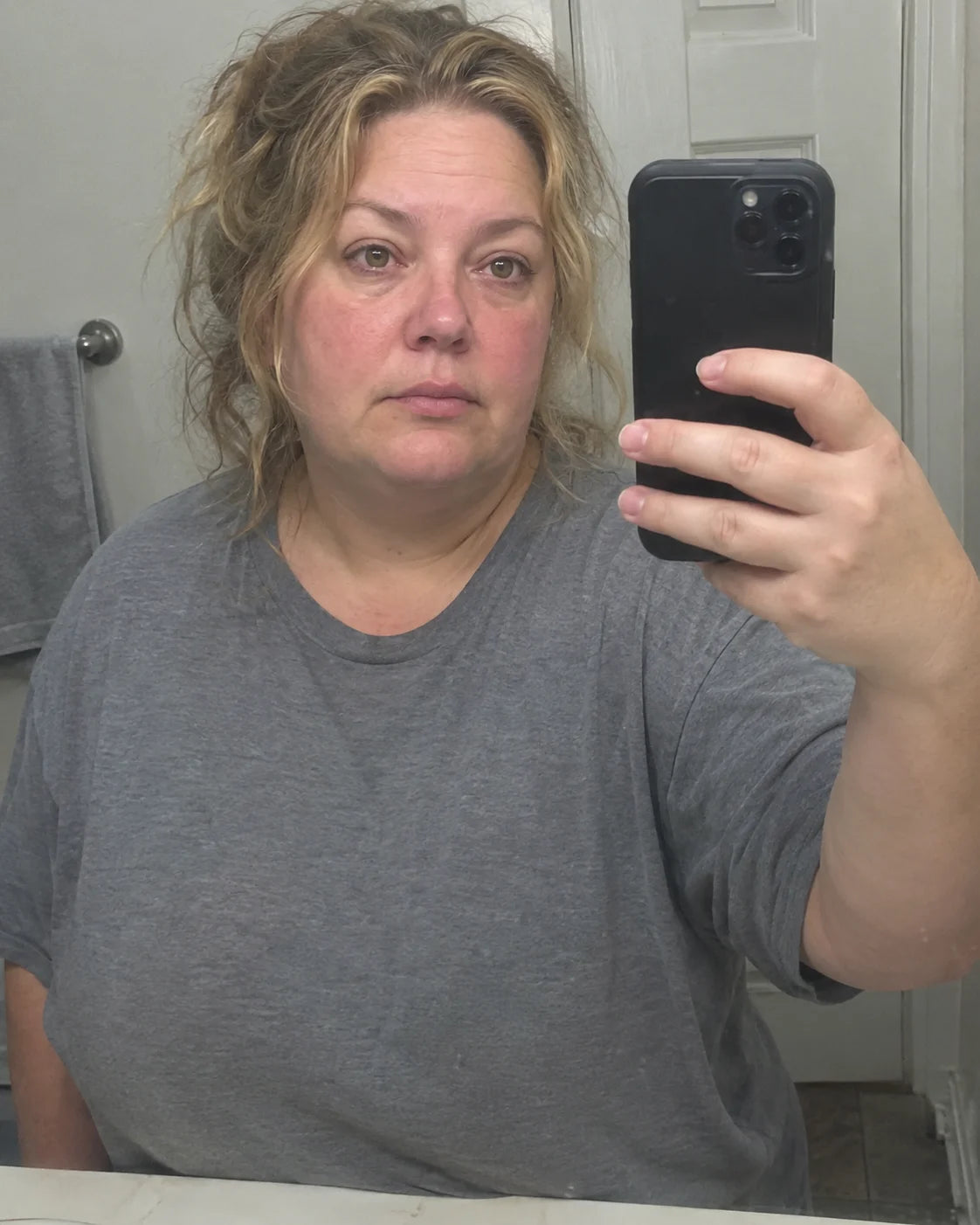 Tired, puffy morning face reflected in a bathroom mirror