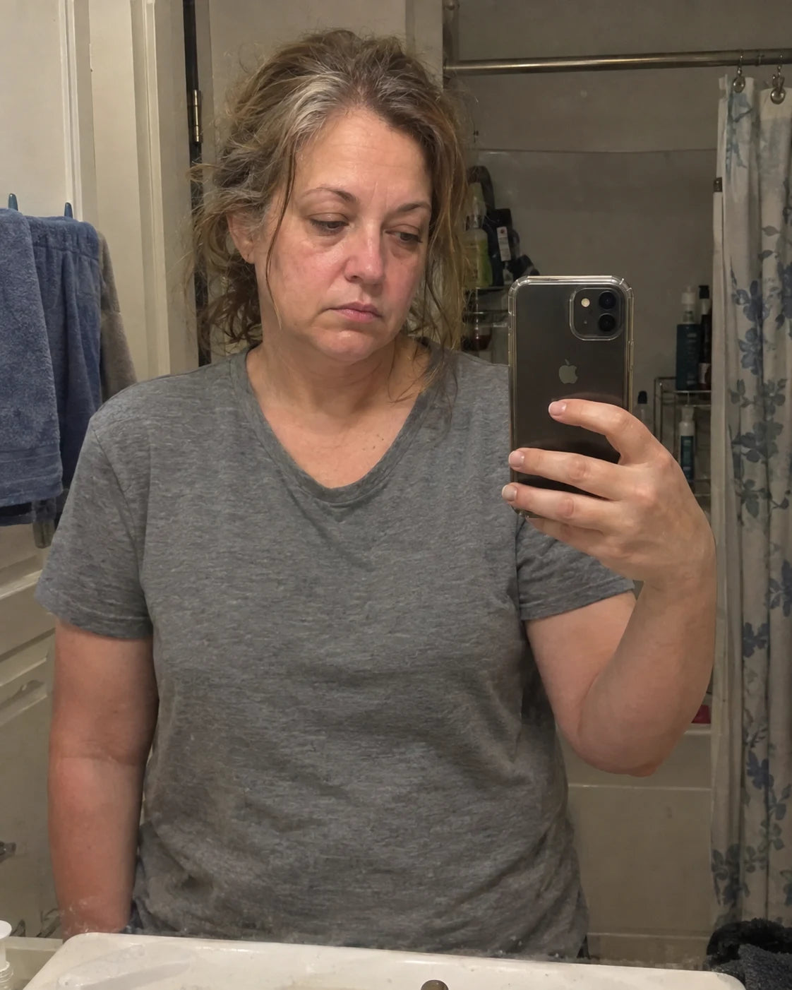 Exhausted, depressed woman taking a mirror selfie in the bathroom