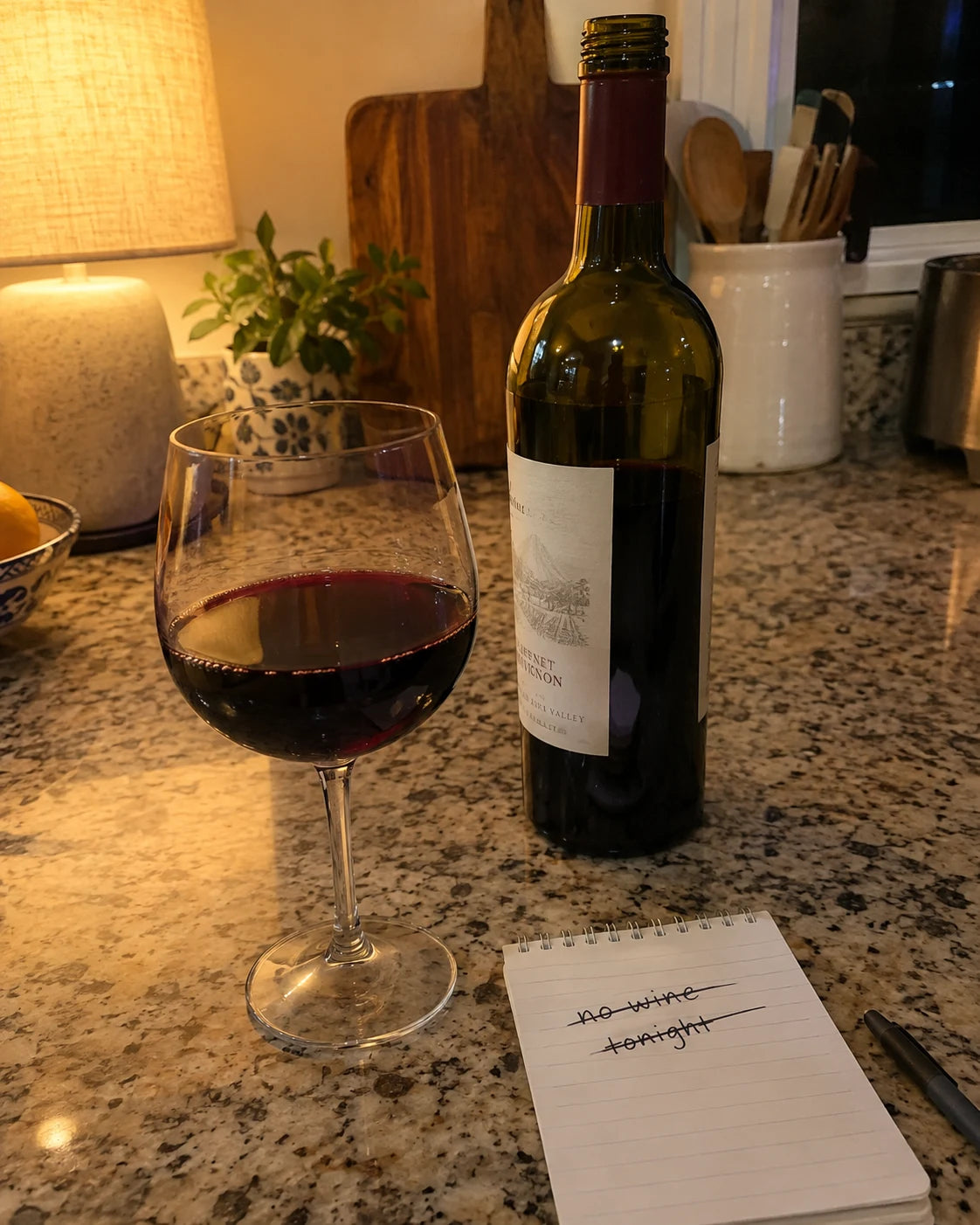 A notepad reading 'no wine tonight' crossed out, next to a freshly poured glass of wine