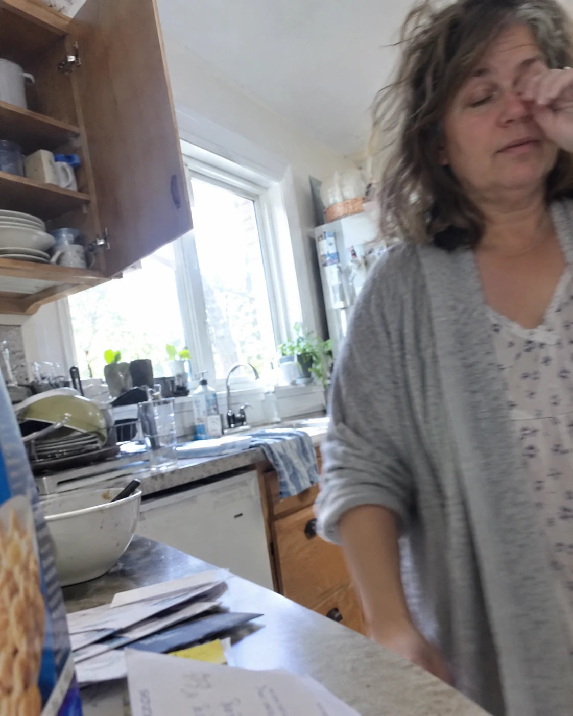 A groggy woman pouring a third cup of coffee in her kitchen