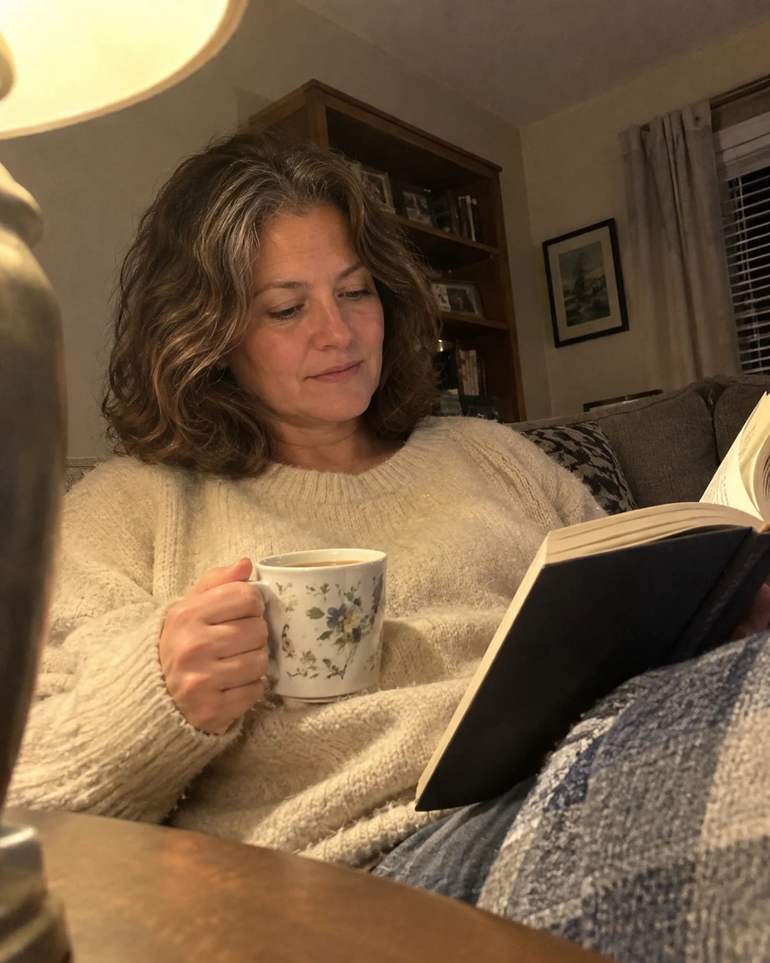 Woman relaxing on the couch in the evening with tea and a book