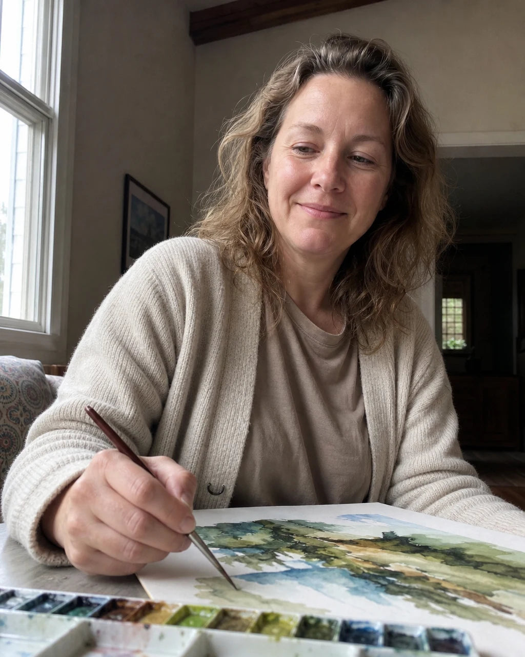 Calm, relaxed woman smiling while painting with a brush at her table
