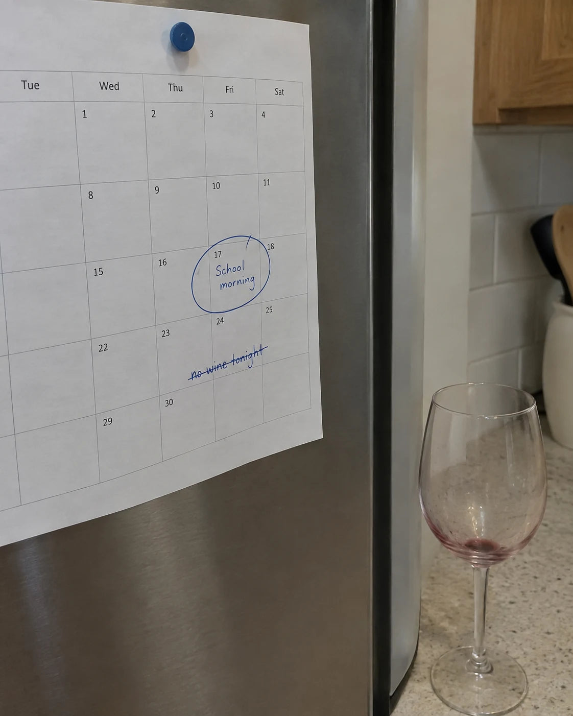 Kitchen calendar with a school morning circled and no wine tonight crossed out, next to an empty wine glass