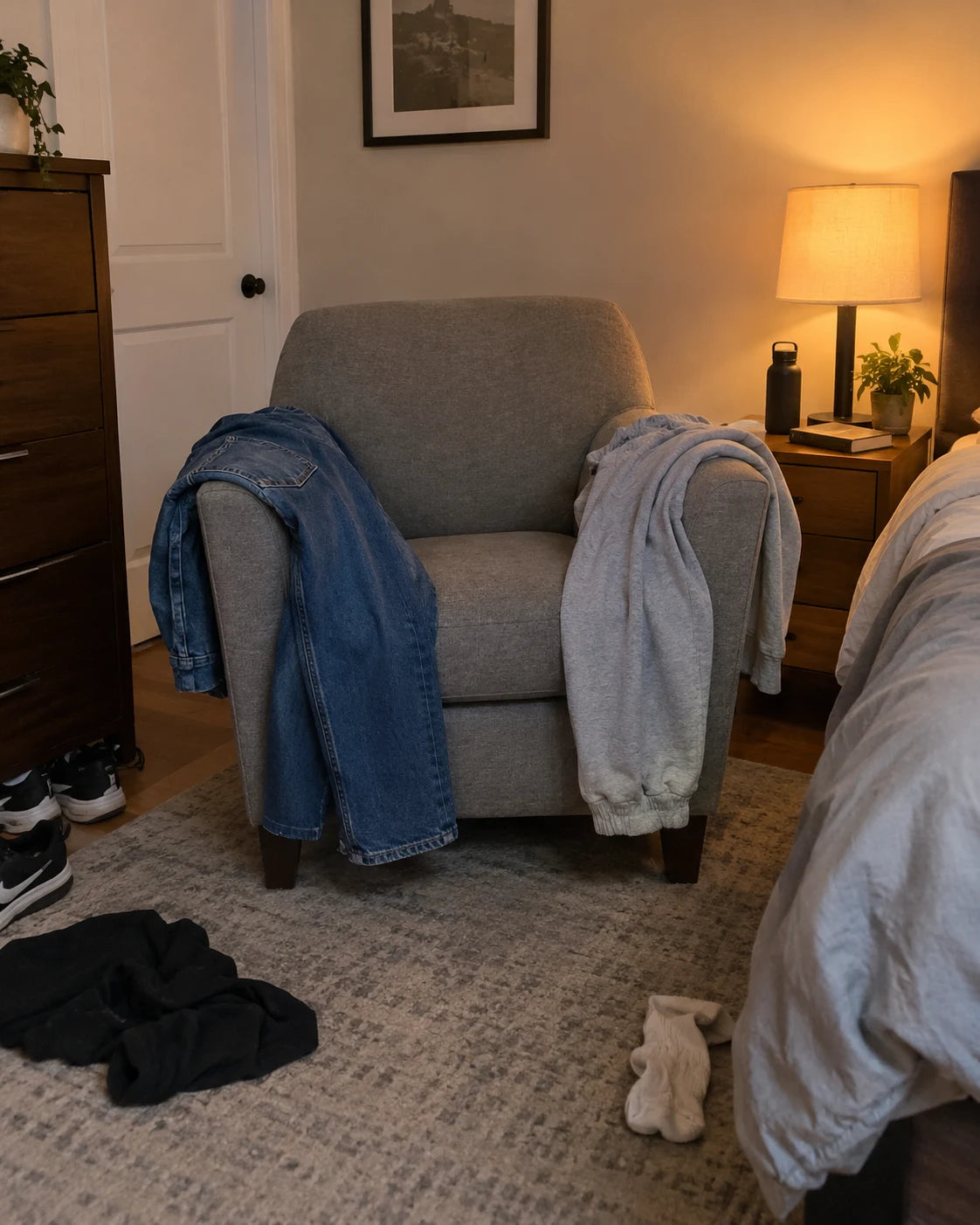 Jeans and sweatpants draped over a cozy armchair in a bedroom at evening