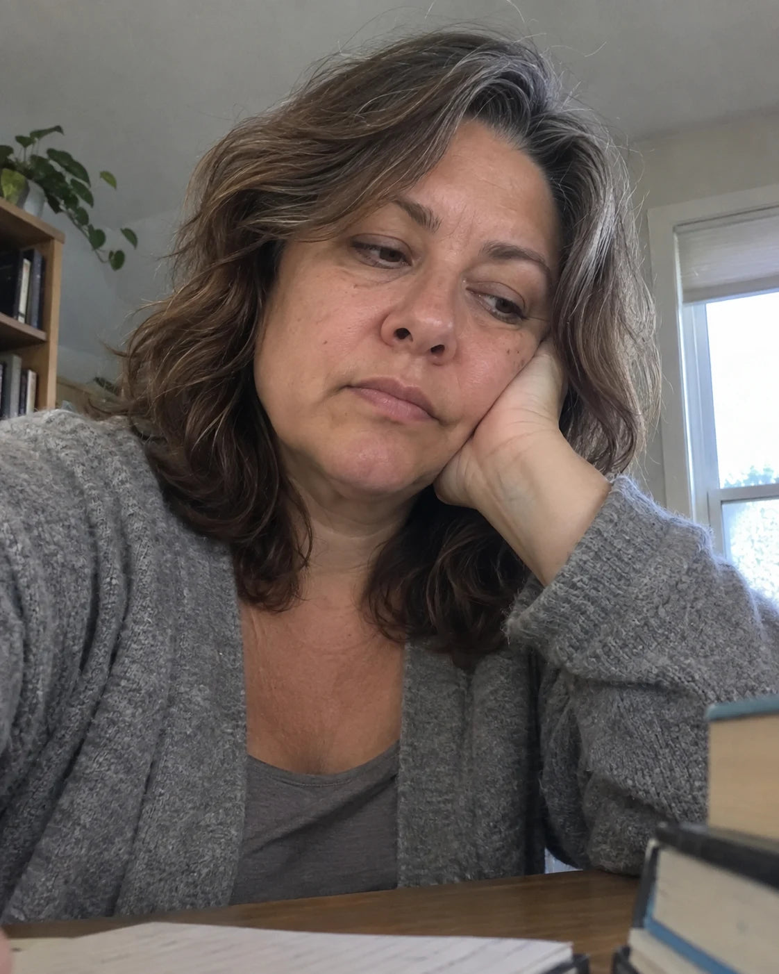 Woman resting her head on her hand at a desk in the afternoon, looking tired