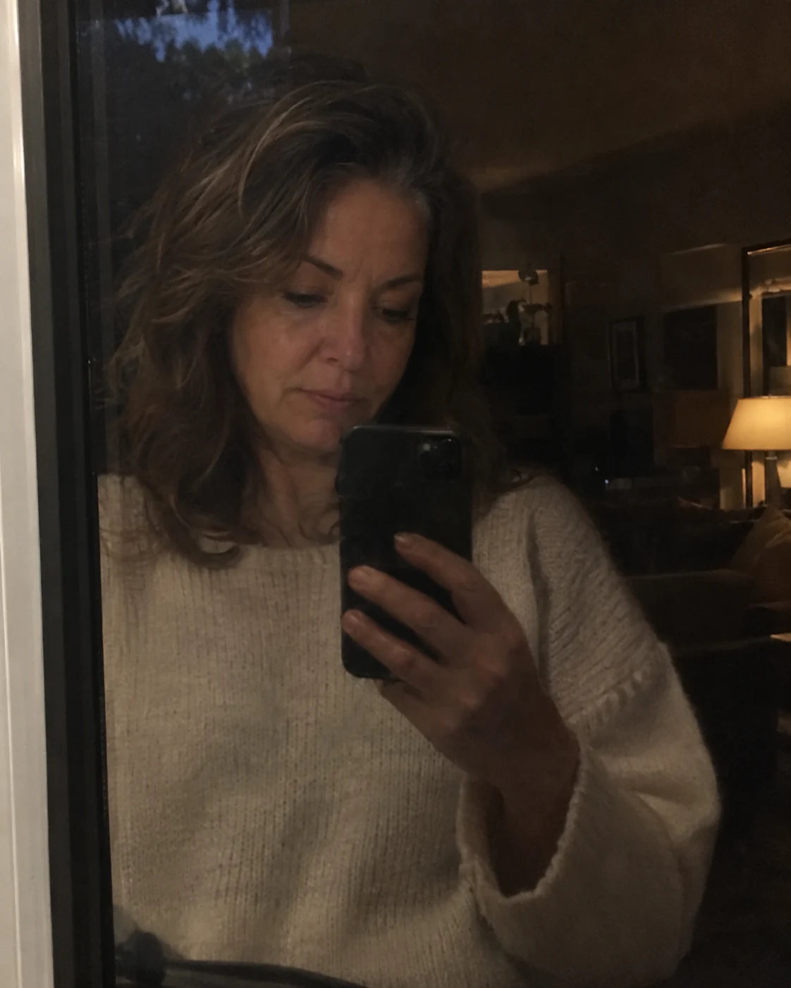 Woman's quiet reflection in a dark window in the evening