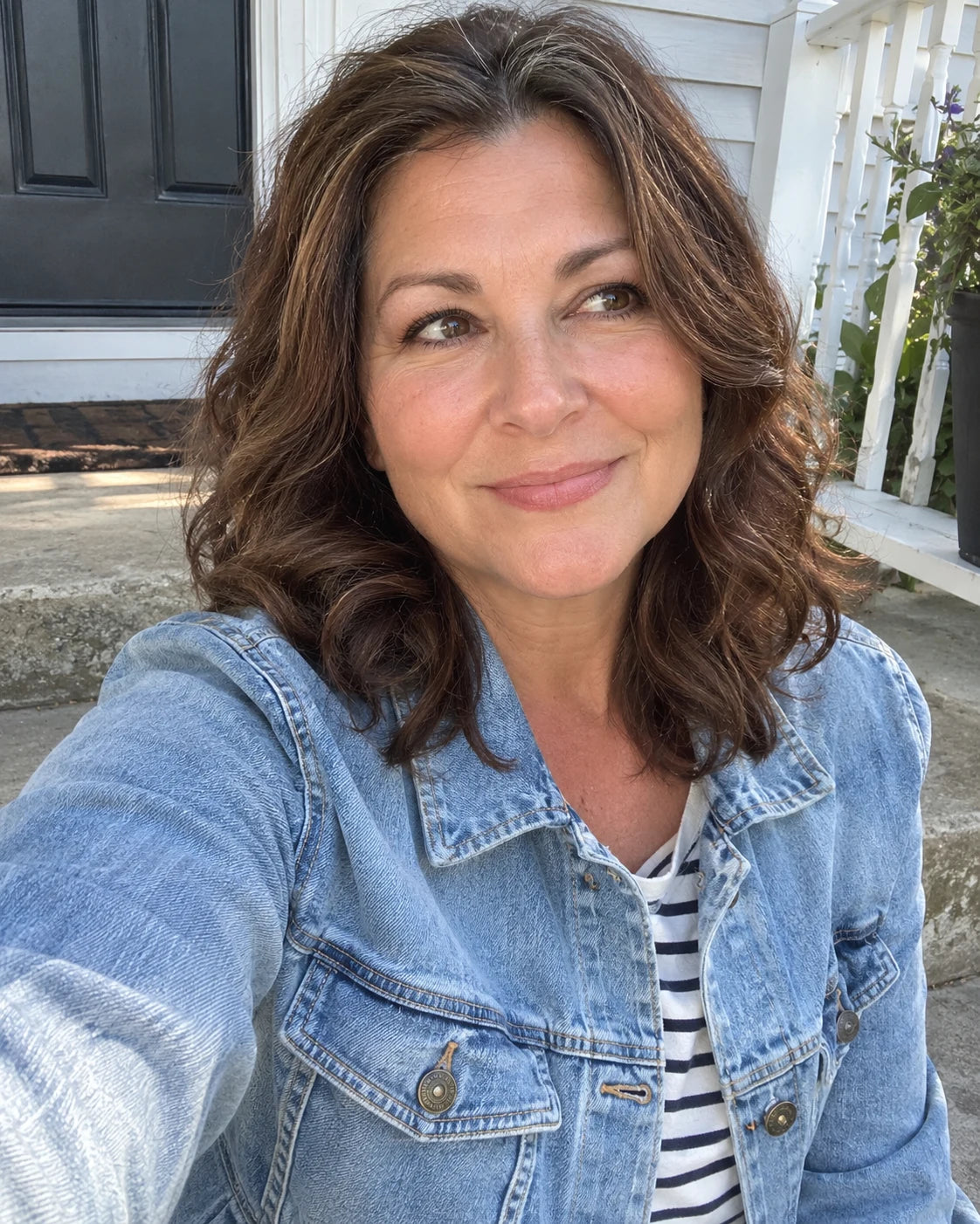Woman smiling on a porch step in the late-afternoon sun