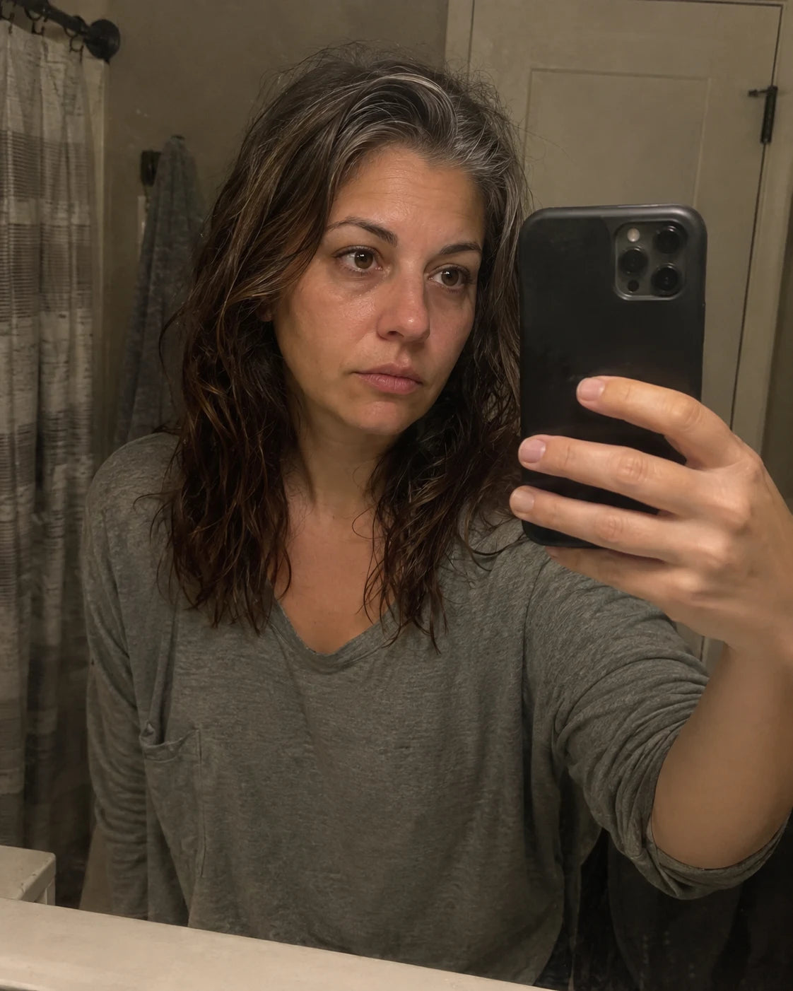 Woman's tired mirror selfie at night, worn expression