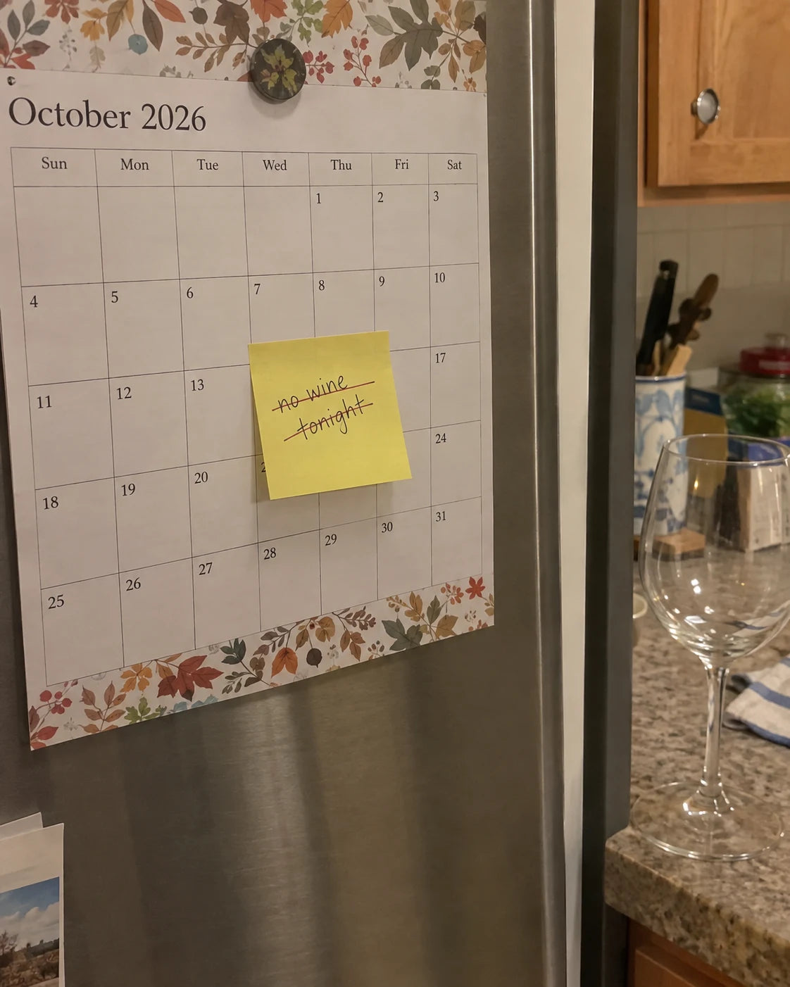 Kitchen calendar with a handwritten note no wine tonight crossed out, next to an empty wine glass