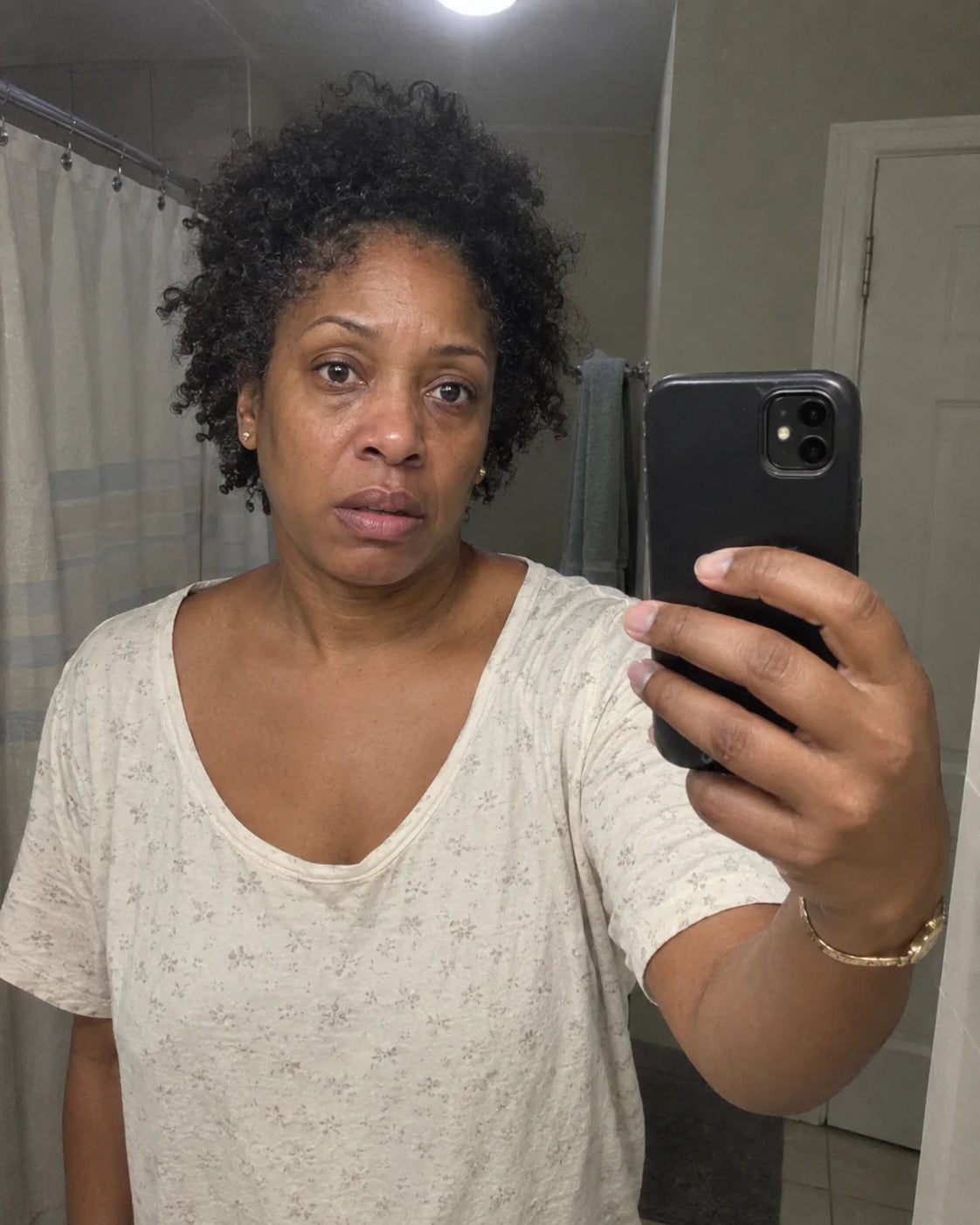 Woman's quiet mirror selfie at night, worn expression