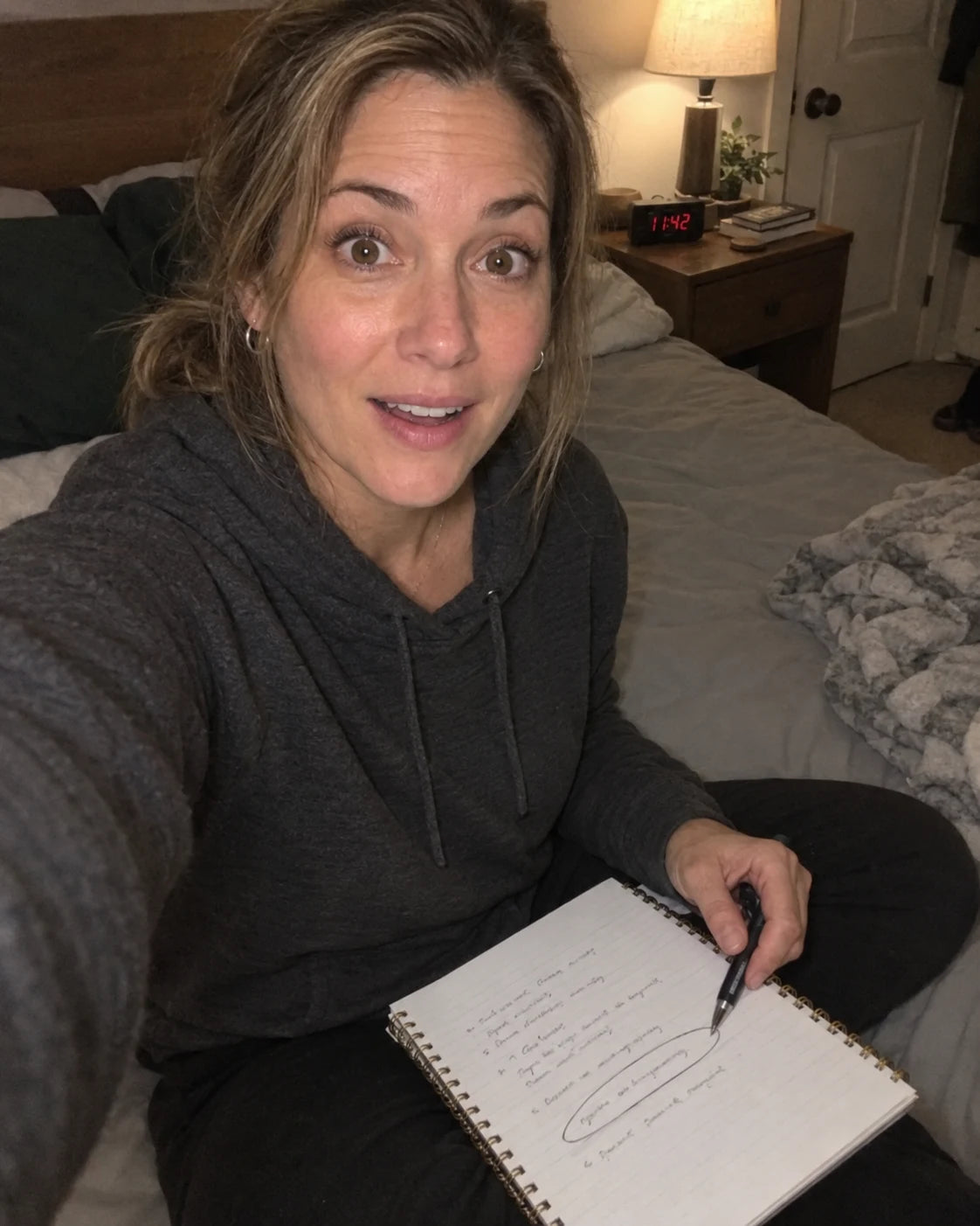 Woman's quiet, thoughtful handheld selfie in her bedroom in the evening
