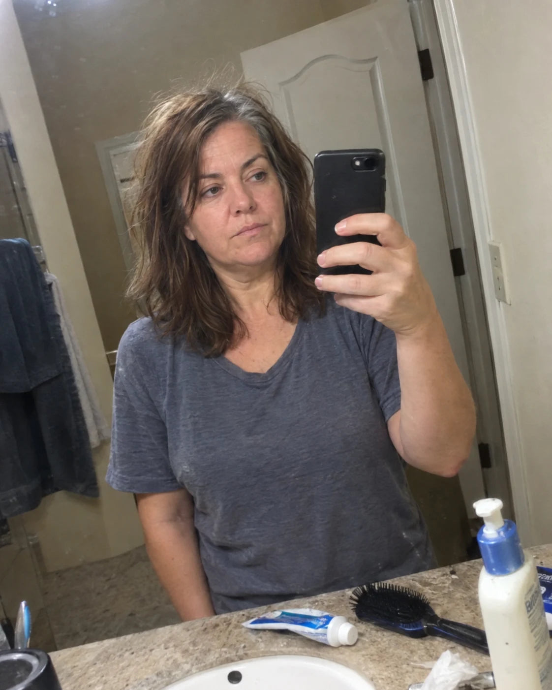 Woman examining her tired reflection in a bathroom mirror selfie