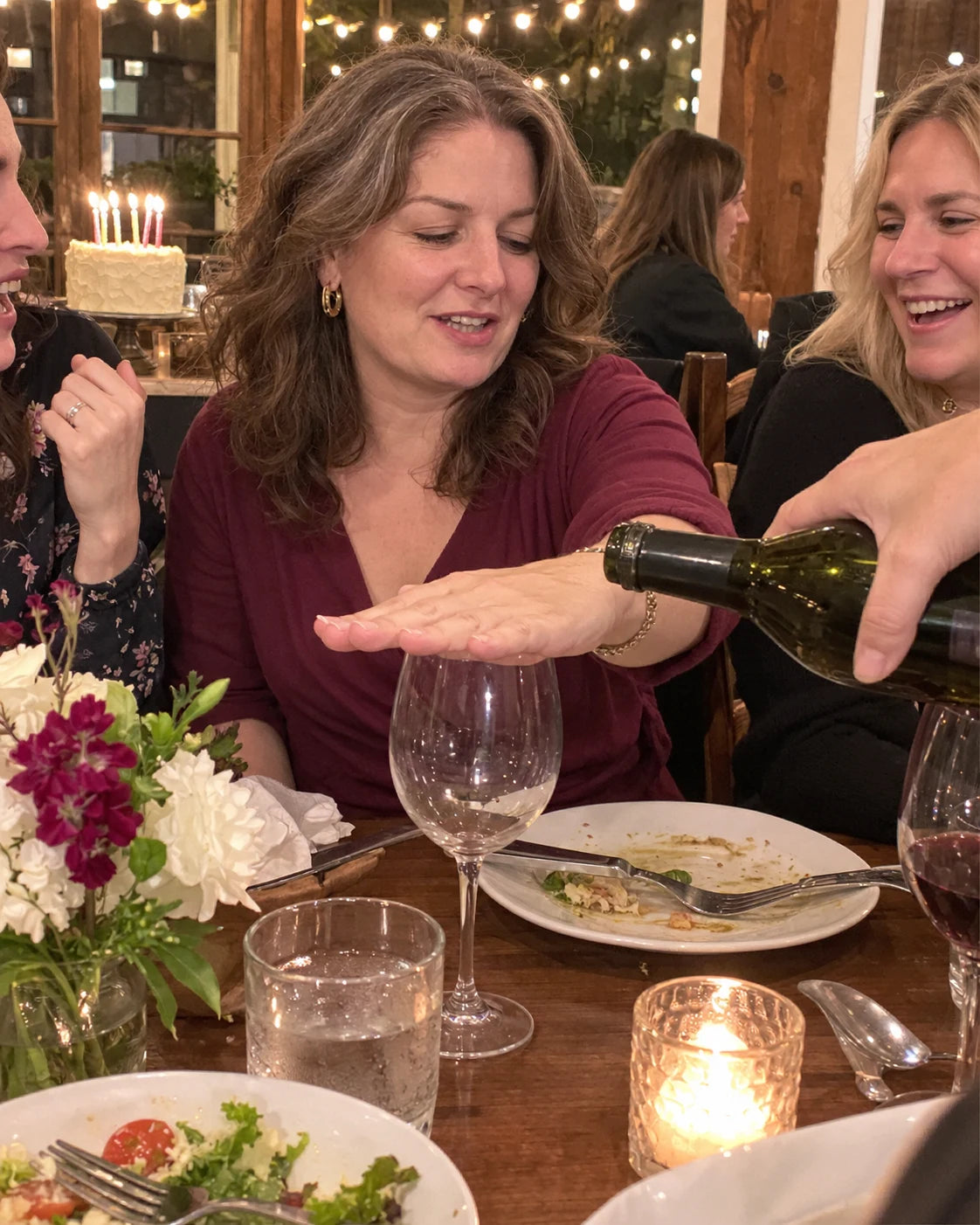Woman covering her wine glass at a birthday dinner table