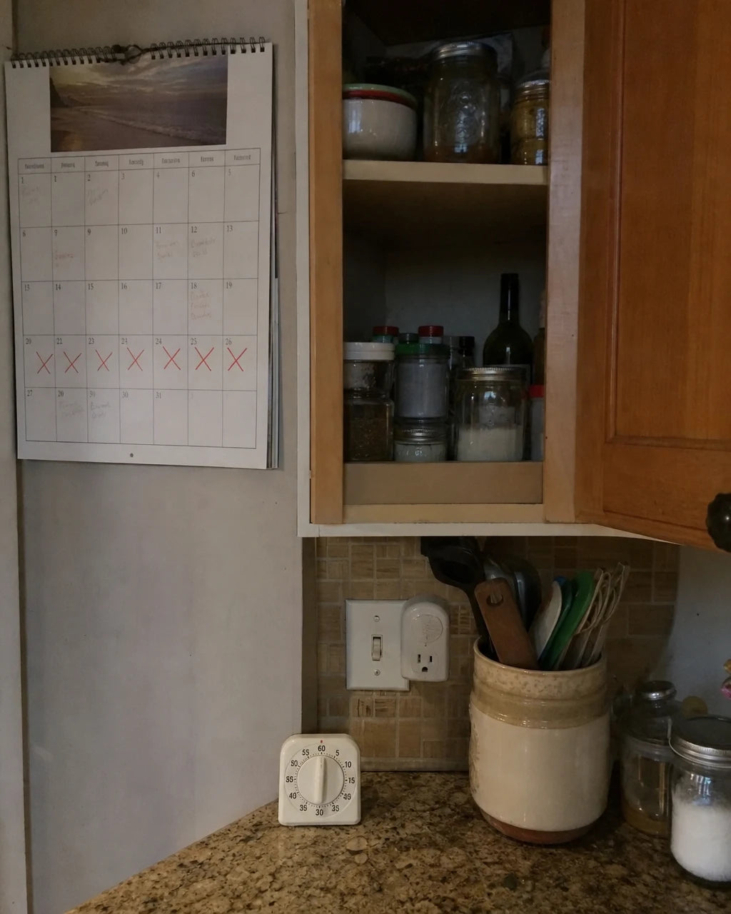 Kitchen counter with a crossed-off calendar, timer, and hidden wine bottle