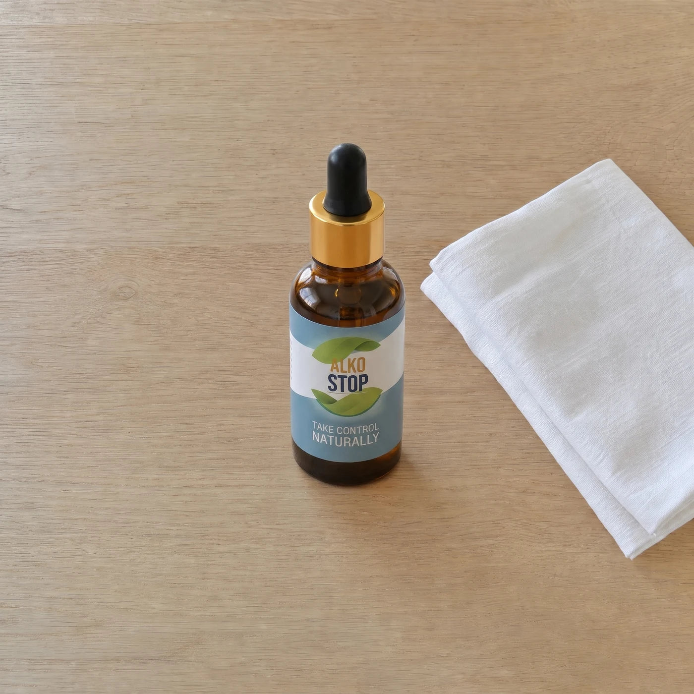 AlkoStop bottle standing on a folded white linen cloth on a wooden table