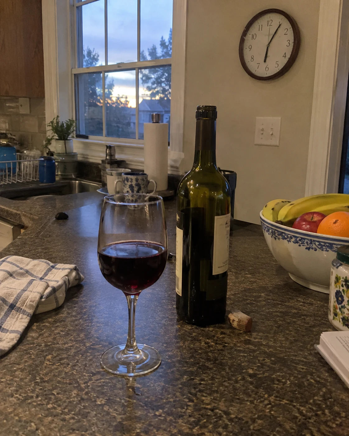 Wine glass and bottle on a kitchen counter at evening