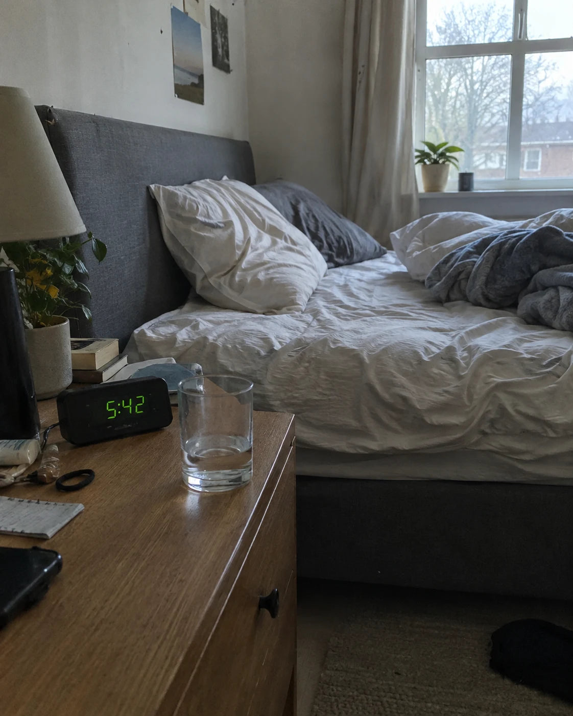 Bedroom nightstand in the morning with a water glass and alarm clock