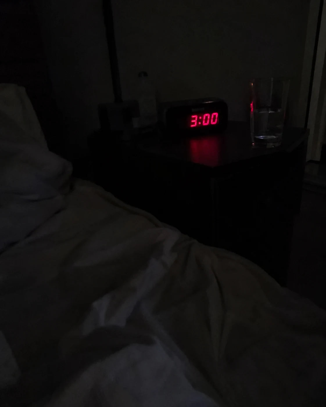 A digital clock reading 3:00 AM on a dark nightstand