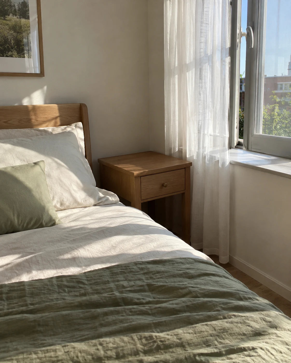 A made bed in soft morning light with an empty nightstand