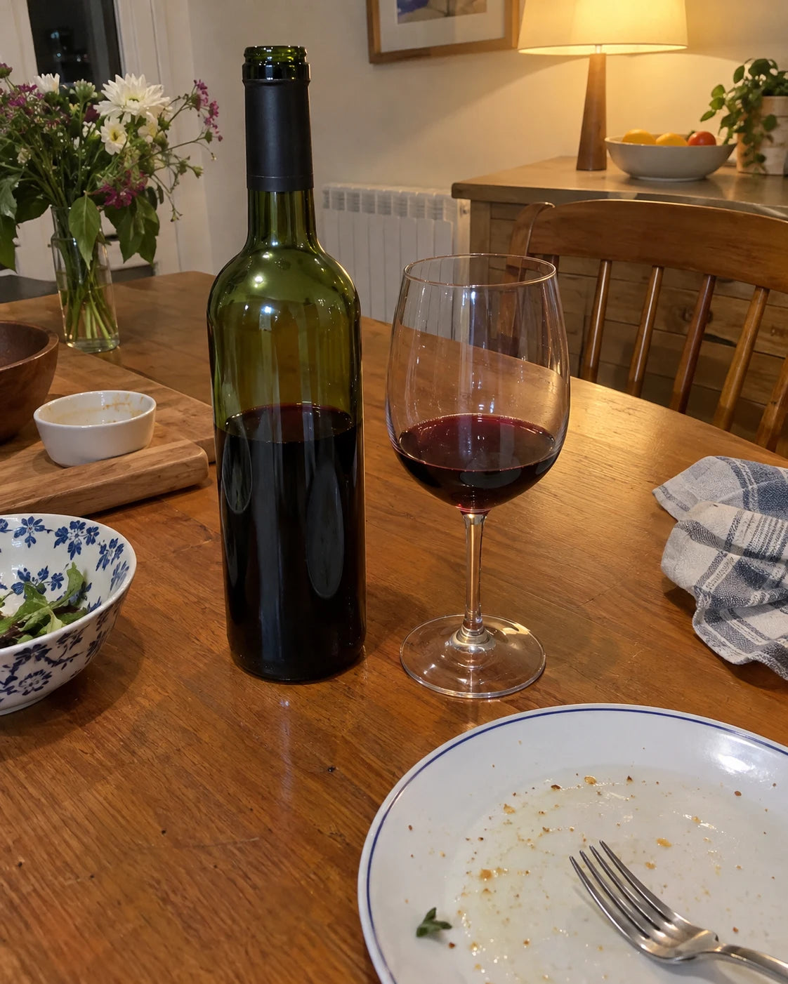 Wine bottle and glass on a kitchen table after dinner, evening light