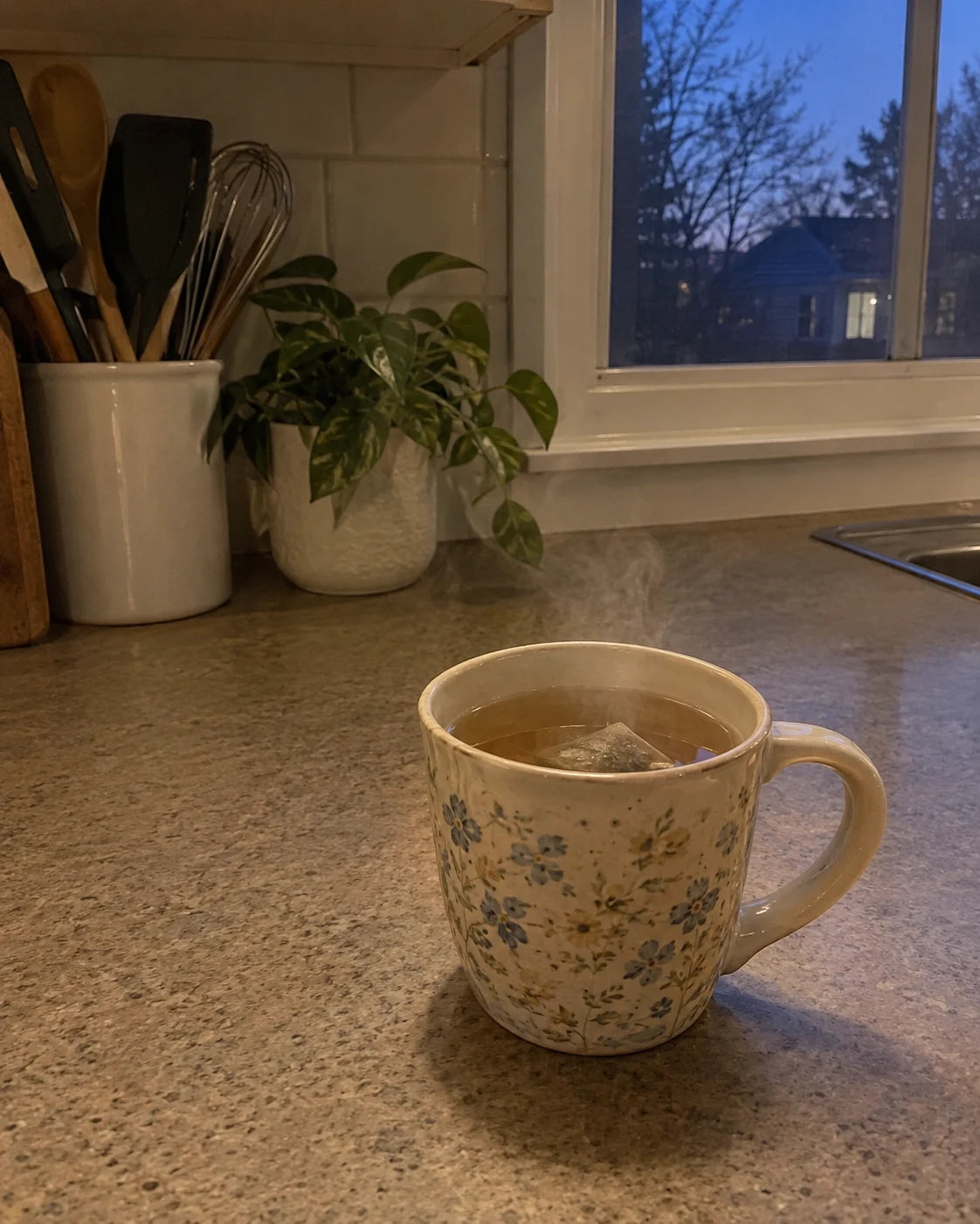 Steaming mug of herbal tea on a kitchen counter at dusk, no wine in sight