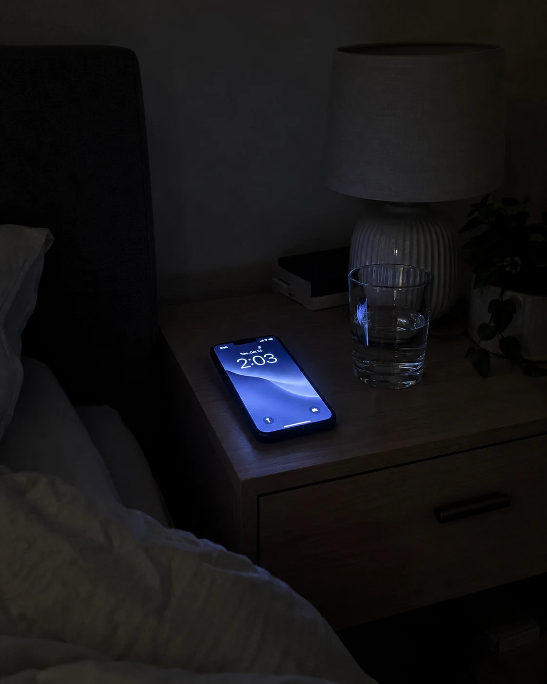 A phone glowing at 2am on a nightstand in a dark bedroom