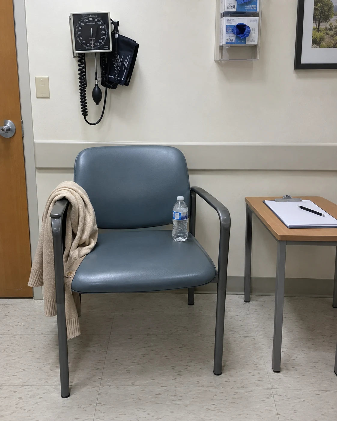 An empty doctor's office waiting room chair with a folded cardigan and a water bottle