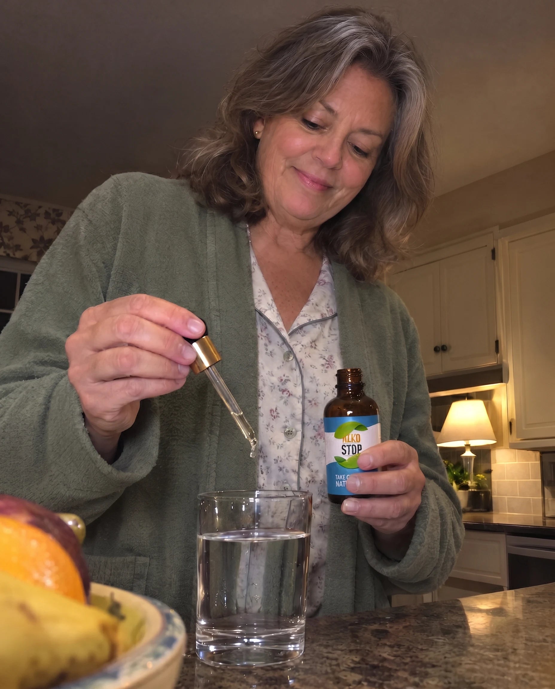 Grandmother in the kitchen at night, squeezing a dropper of AlkoStop into a glass of water