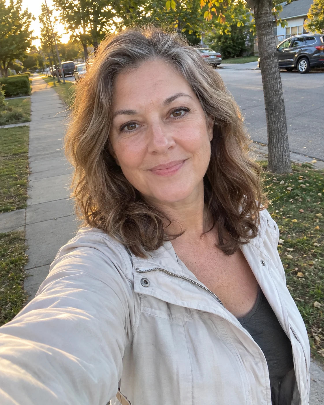 Woman smiling on a walk outdoors at golden hour, relaxed and content