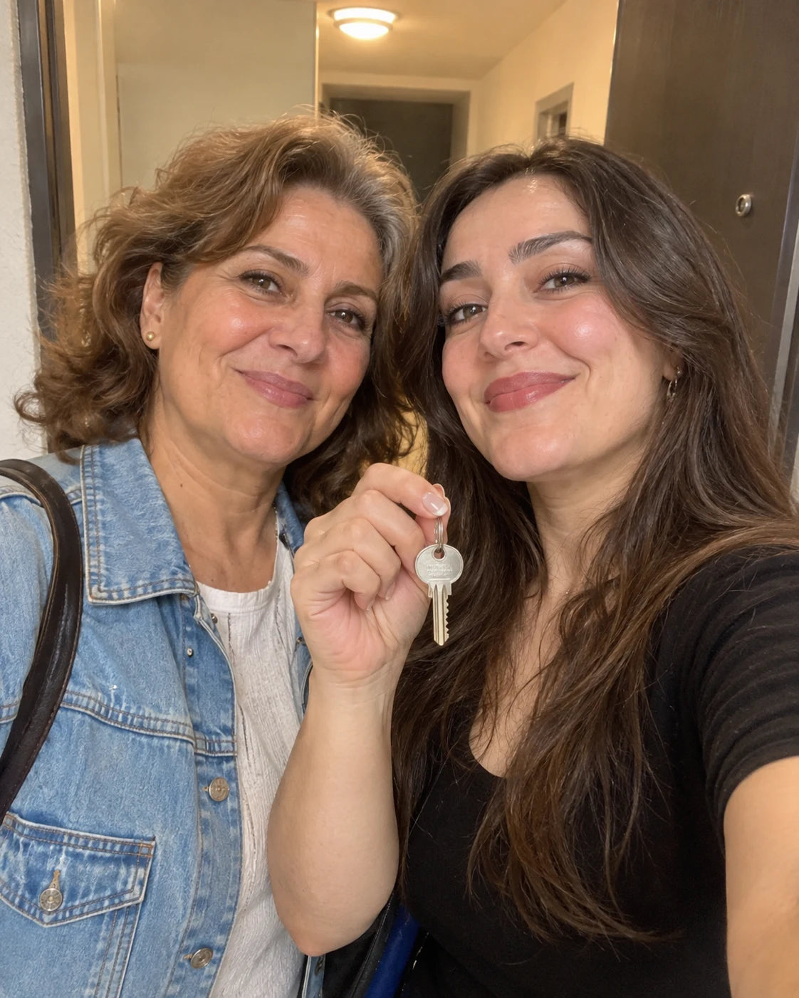Woman smiling with her adult daughter holding a key to her new apartment